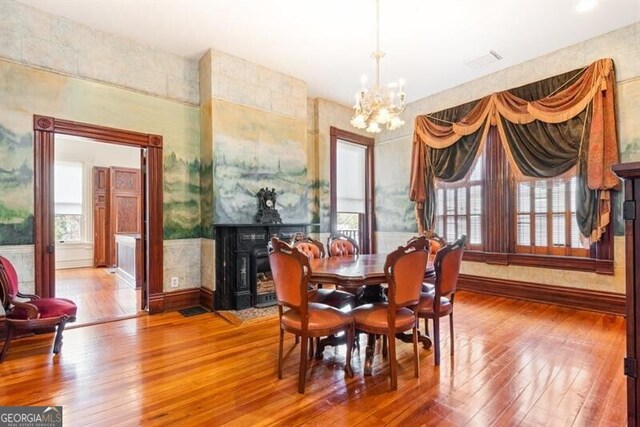 dining space featuring a chandelier, hardwood / wood-style floors, and a tile fireplace