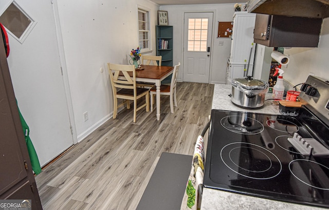 kitchen with light hardwood / wood-style floors, range hood, and stainless steel electric range