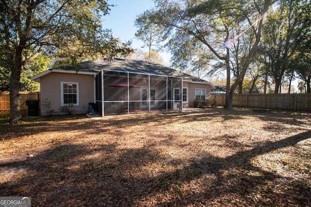 back of property with a fenced backyard and a sunroom