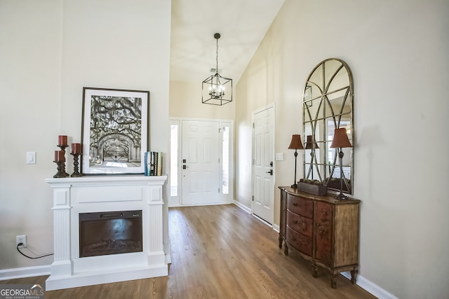 foyer entrance with a notable chandelier, vaulted ceiling, and hardwood / wood-style flooring