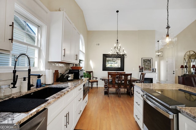 kitchen with sink, white cabinetry, hanging light fixtures, and stainless steel appliances