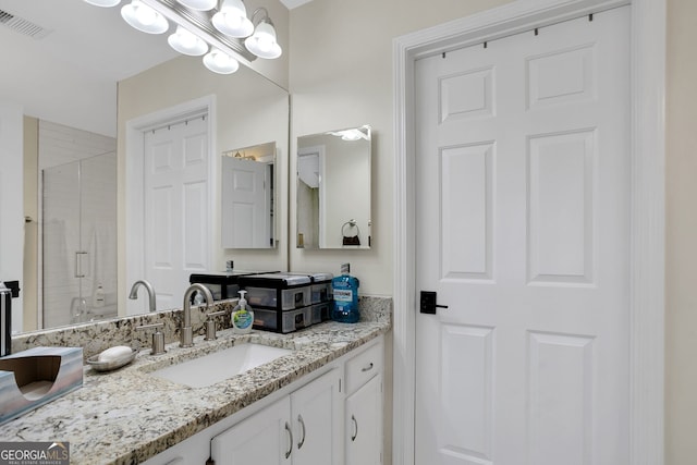 bathroom featuring a shower with door and vanity