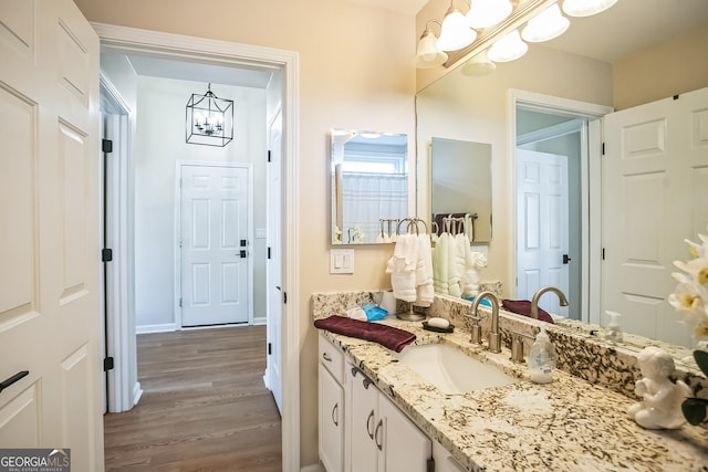 bathroom with an inviting chandelier, vanity, and hardwood / wood-style flooring