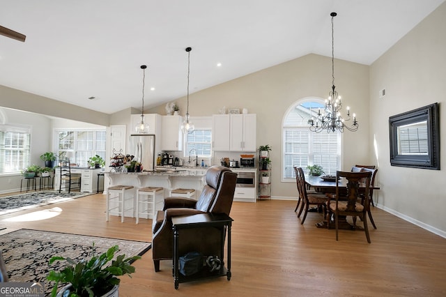 living room with light hardwood / wood-style floors, sink, high vaulted ceiling, and a chandelier