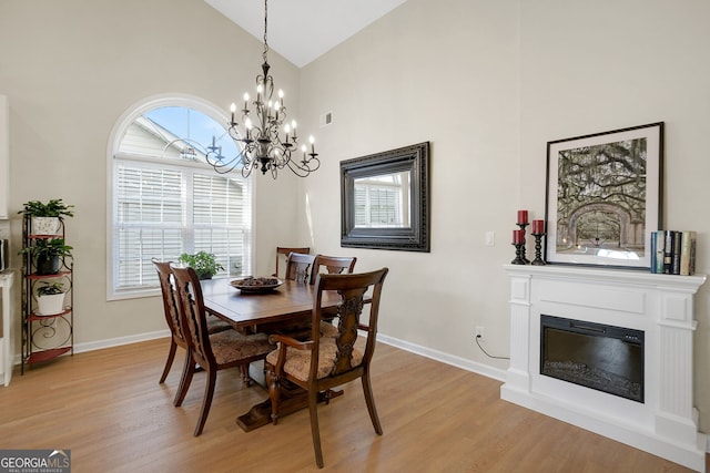 dining room with a notable chandelier, high vaulted ceiling, and light hardwood / wood-style flooring