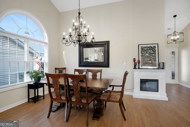 dining space with hardwood / wood-style floors, an inviting chandelier, and lofted ceiling