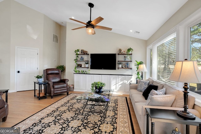 living room featuring ceiling fan, light hardwood / wood-style floors, and vaulted ceiling