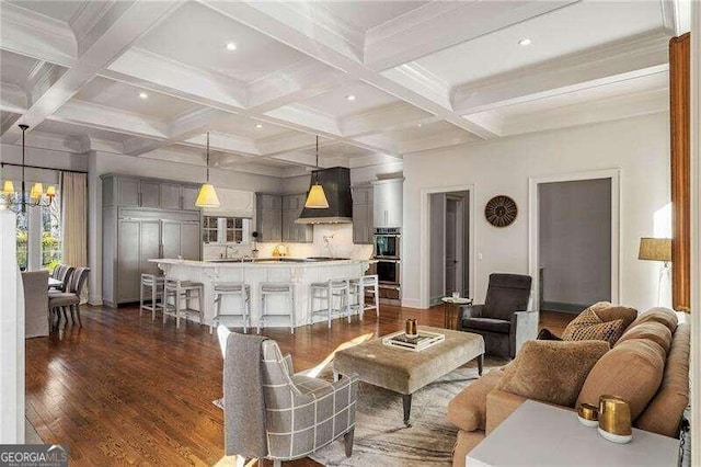 living room featuring beamed ceiling, dark hardwood / wood-style floors, a notable chandelier, and coffered ceiling