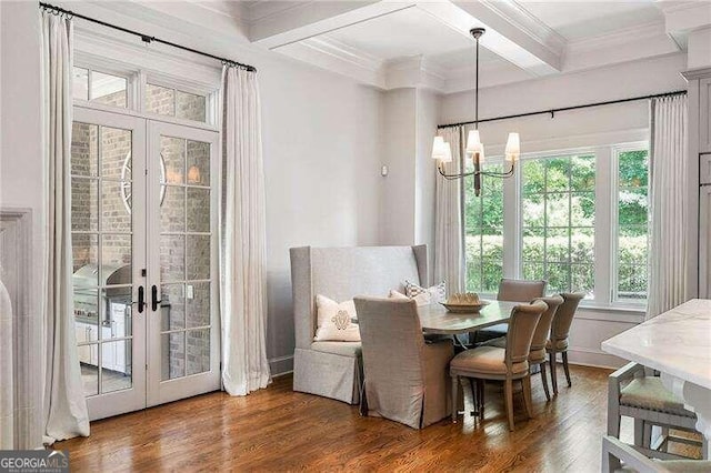 dining area featuring french doors, beamed ceiling, a notable chandelier, wood-type flooring, and ornamental molding