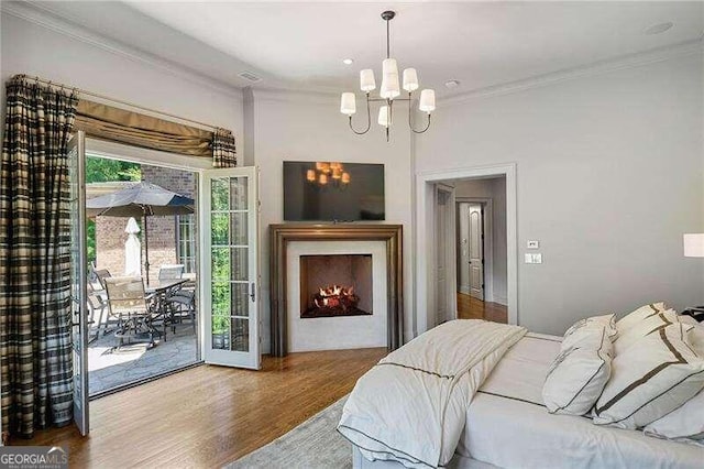 bedroom featuring access to exterior, wood-type flooring, a chandelier, and crown molding