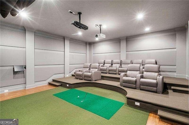 home theater room with hardwood / wood-style flooring and golf simulator