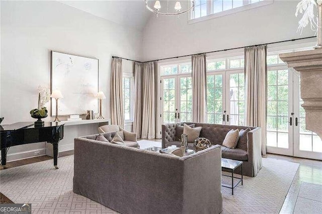 living room with french doors, light wood-type flooring, an inviting chandelier, and high vaulted ceiling