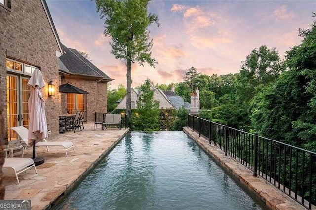 pool at dusk featuring a patio area