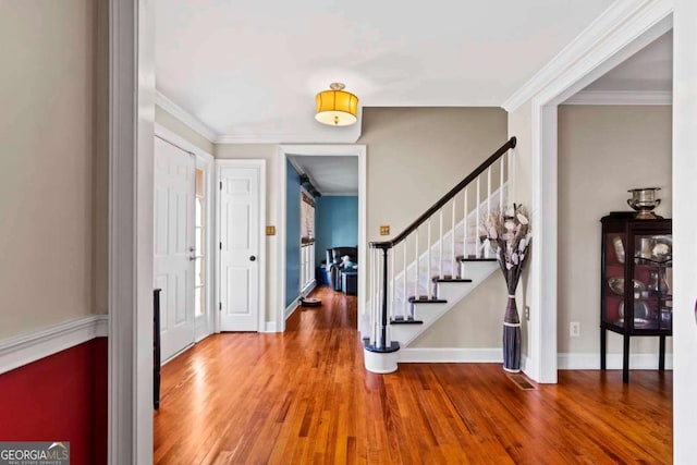 foyer with wood-type flooring and crown molding