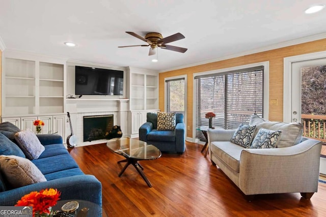 living room featuring a fireplace, built in shelves, dark hardwood / wood-style floors, and ceiling fan