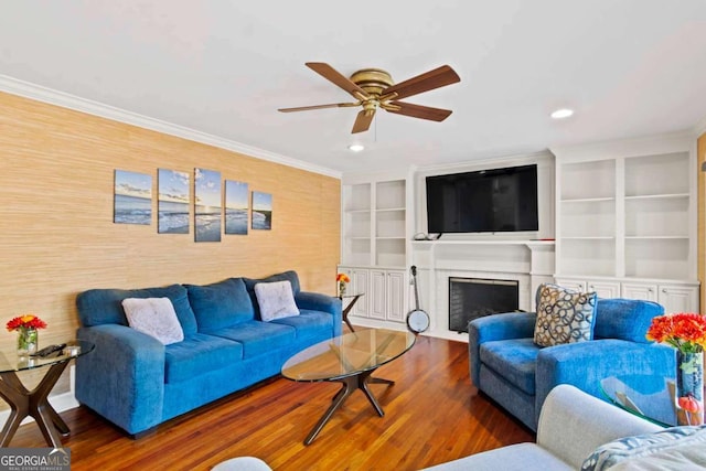 living room featuring a brick fireplace, ornamental molding, ceiling fan, built in features, and dark hardwood / wood-style floors