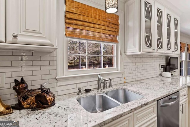 kitchen featuring decorative backsplash, light stone countertops, stainless steel dishwasher, sink, and white cabinetry