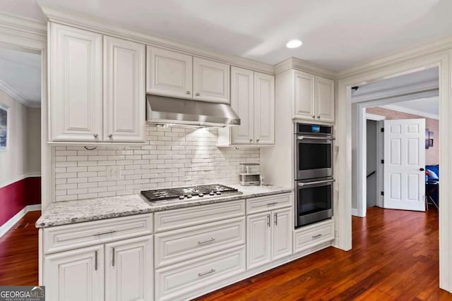 kitchen with light stone counters, white cabinets, dark wood-type flooring, and appliances with stainless steel finishes