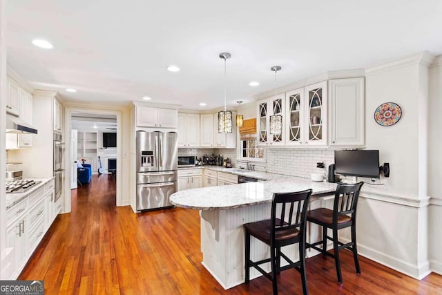 kitchen featuring kitchen peninsula, white cabinetry, decorative light fixtures, and appliances with stainless steel finishes