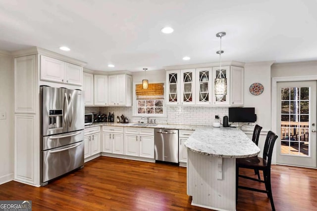 kitchen with white cabinetry, hanging light fixtures, kitchen peninsula, a breakfast bar, and appliances with stainless steel finishes