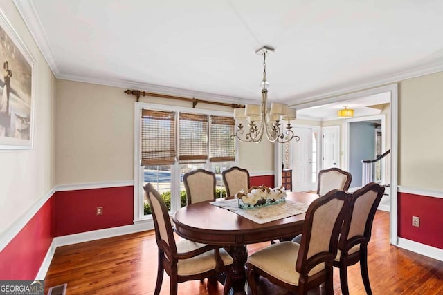 dining area with an inviting chandelier, dark wood-type flooring, and ornamental molding