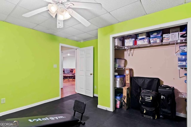 workout area with a paneled ceiling and ceiling fan