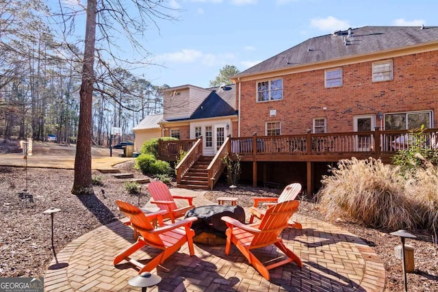 back of property featuring a fire pit, a patio area, and a wooden deck