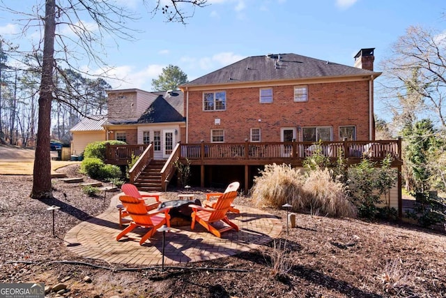 back of property with a wooden deck and a fire pit