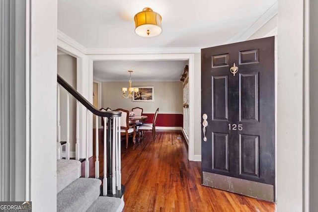 foyer entrance with crown molding, dark hardwood / wood-style floors, and a notable chandelier