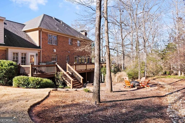 rear view of house with a wooden deck and a fire pit