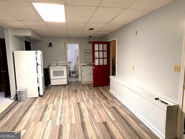 kitchen featuring hardwood / wood-style flooring, a drop ceiling, white appliances, and sink