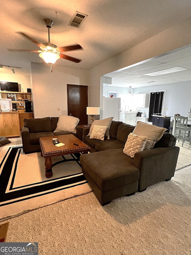 carpeted living room with ceiling fan and a textured ceiling