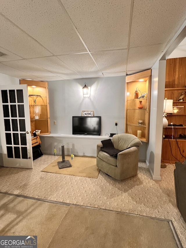 living room featuring carpet flooring and a drop ceiling