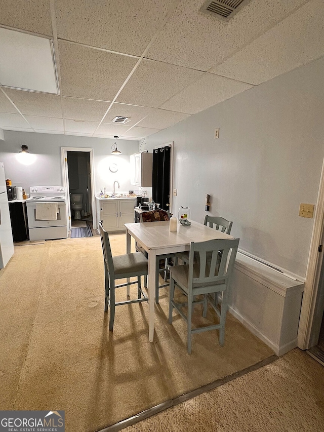 dining space with carpet flooring, a drop ceiling, and sink