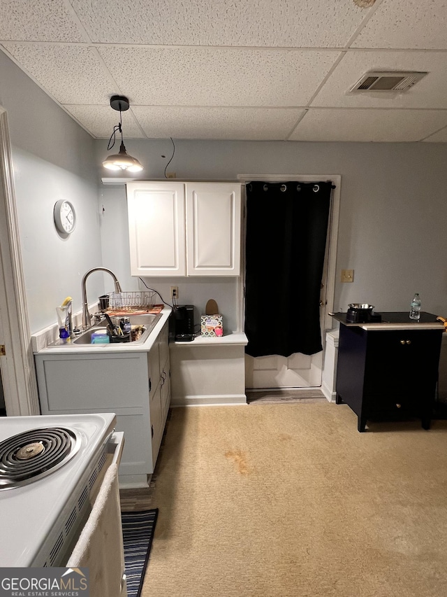 kitchen featuring a paneled ceiling, decorative light fixtures, white cabinetry, and sink