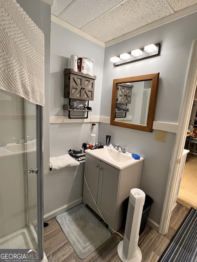 bathroom with a paneled ceiling, vanity, a shower with door, crown molding, and wood-type flooring