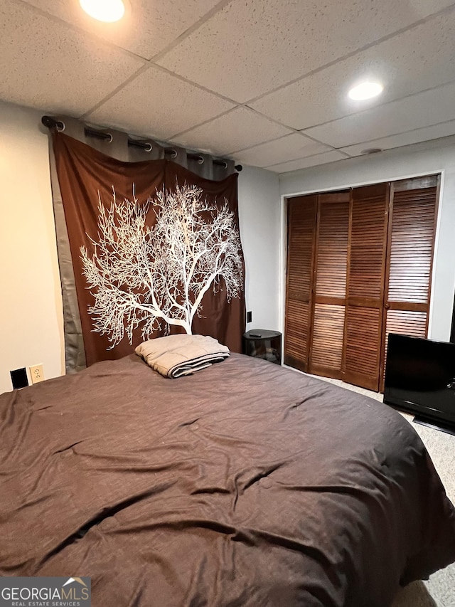 bedroom with a paneled ceiling and a closet