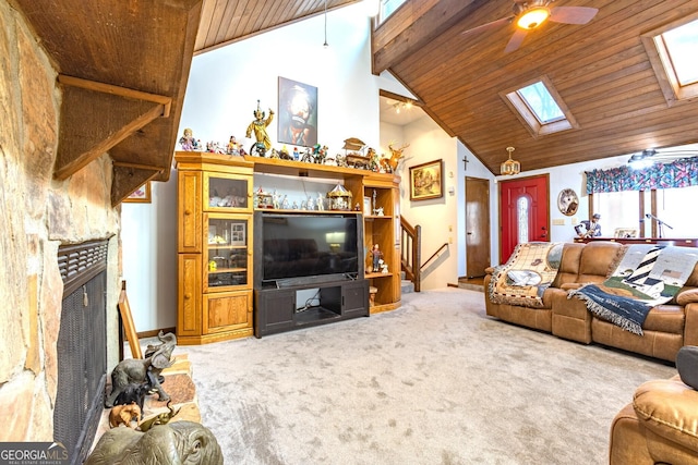 carpeted living room with wooden ceiling, high vaulted ceiling, a skylight, ceiling fan, and a fireplace