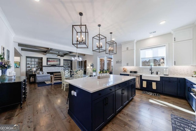 kitchen with a kitchen island, beamed ceiling, white cabinetry, sink, and ceiling fan