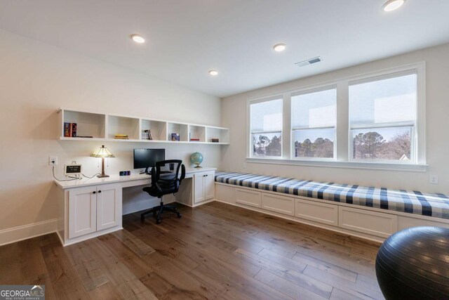 office space with dark hardwood / wood-style flooring, built in desk, and plenty of natural light