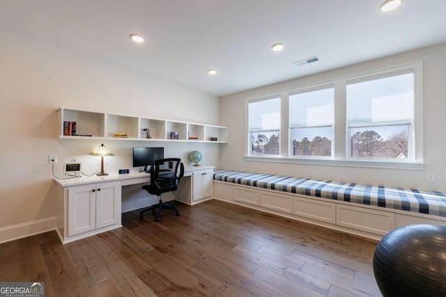 office area featuring plenty of natural light, dark hardwood / wood-style floors, and built in desk