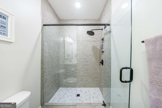 bathroom featuring a shower with shower door and toilet