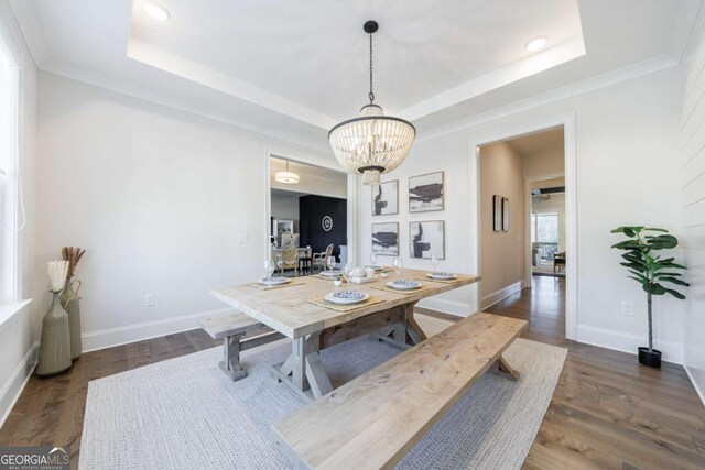 dining space with dark hardwood / wood-style floors, a raised ceiling, and a notable chandelier