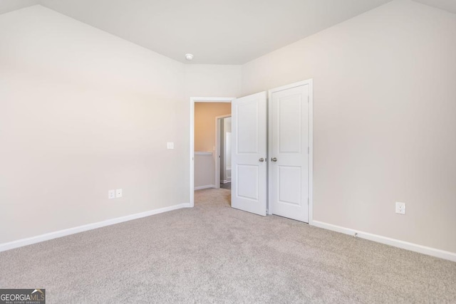 unfurnished bedroom with lofted ceiling and light colored carpet