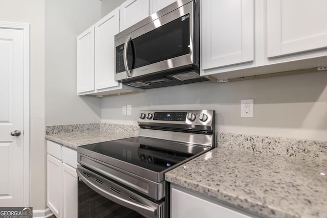 kitchen featuring stainless steel appliances, light stone countertops, and white cabinets