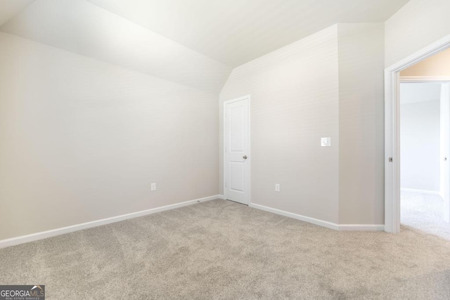 carpeted spare room featuring vaulted ceiling