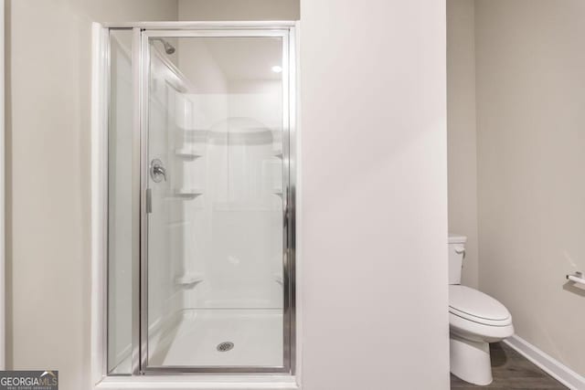 bathroom with wood-type flooring, an enclosed shower, and toilet