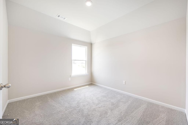 spare room with carpet flooring and vaulted ceiling