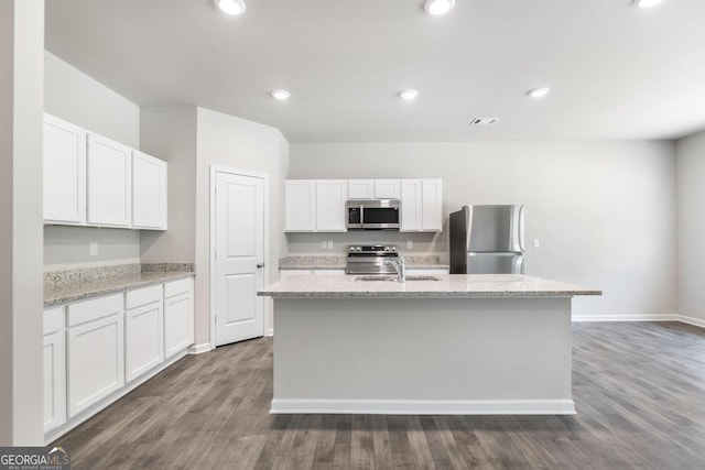 kitchen with white cabinetry, an island with sink, sink, stainless steel appliances, and light stone countertops