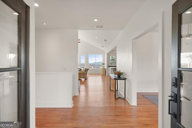 hall with light wood-type flooring and vaulted ceiling